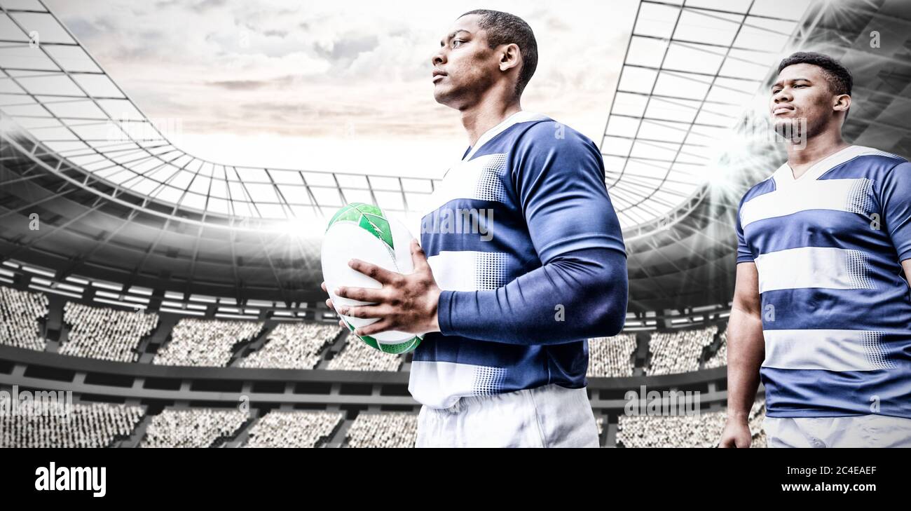 Immagine digitale composita di due giocatori di rugby che tengono la palla nello stadio sportivo Foto Stock