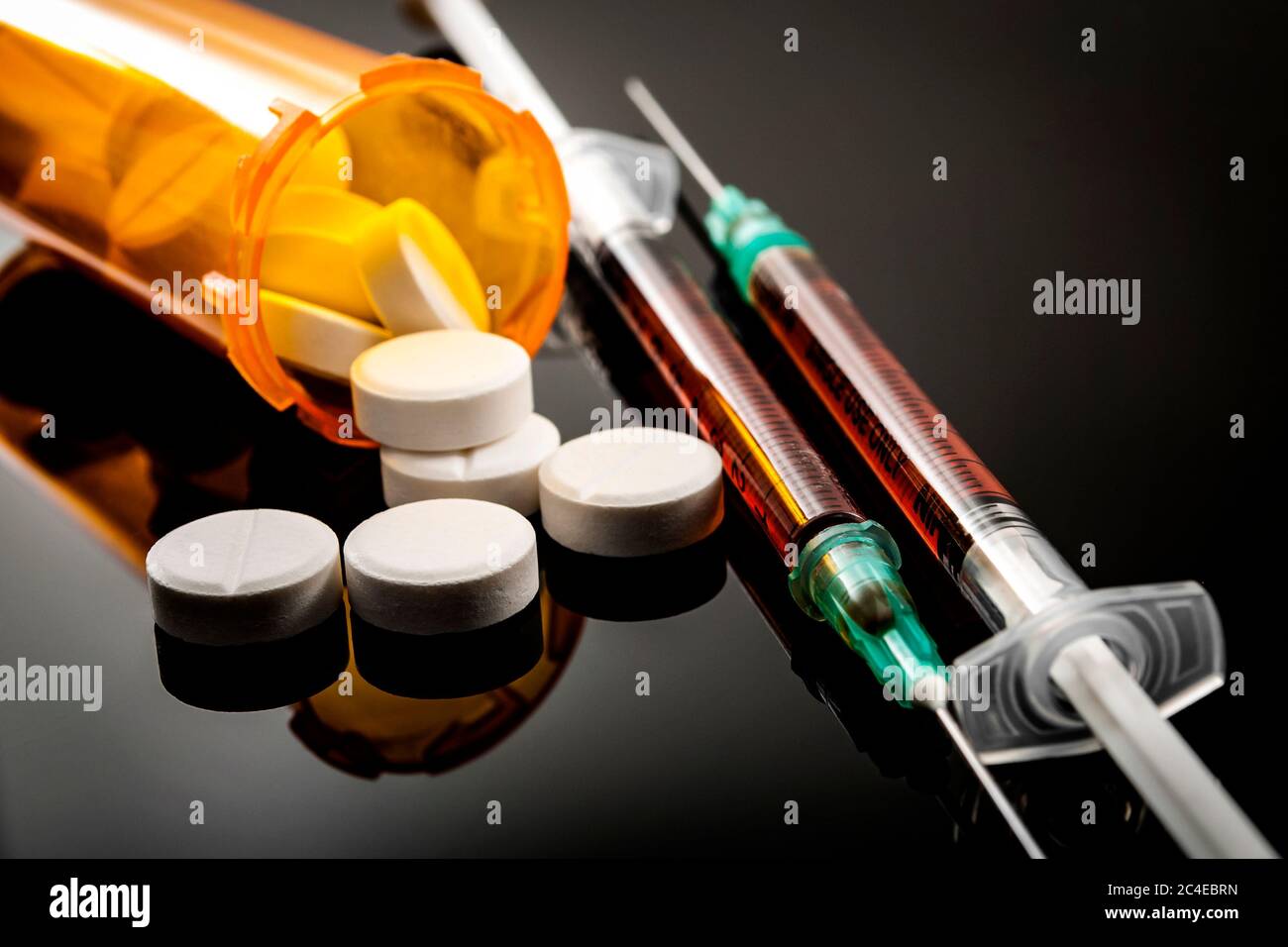 Epidemia di oppioidi, concetto di abuso di droga con closeup su due siringhe di eroina o altri narcotici circondati da oppioidi prescrizione sparsi. L'ossicodone è Foto Stock