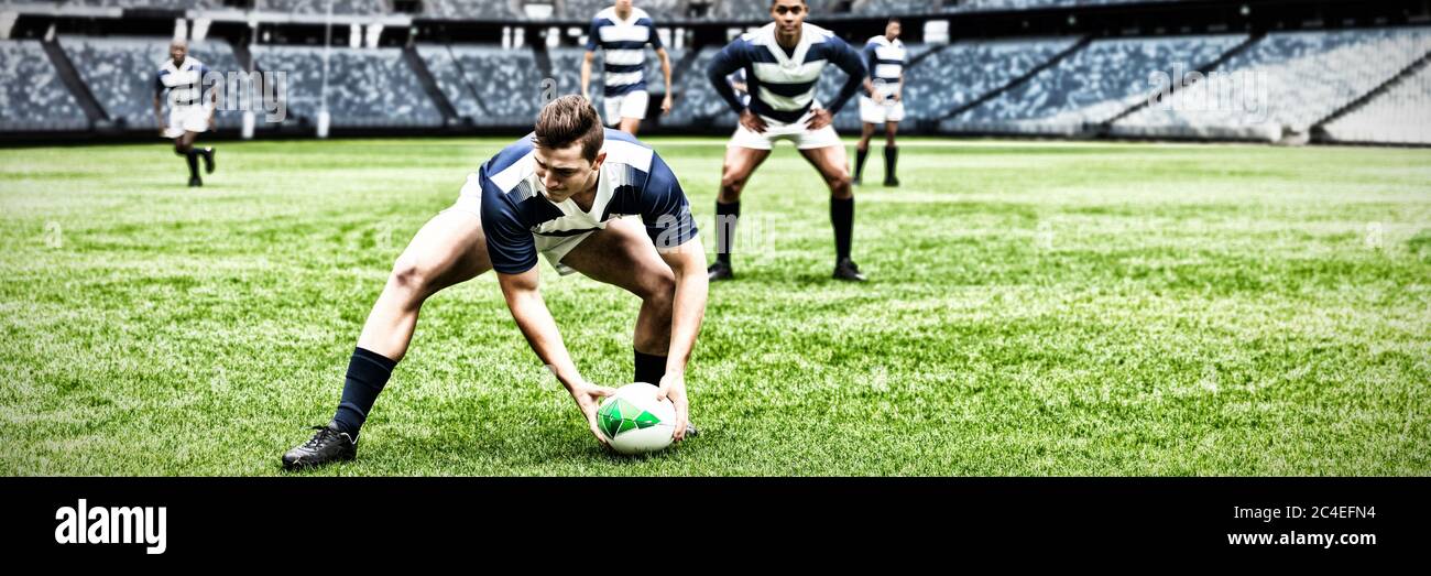 Immagine digitale composita del giocatore di rugby che raccoglie la palla nello stadio sportivo Foto Stock