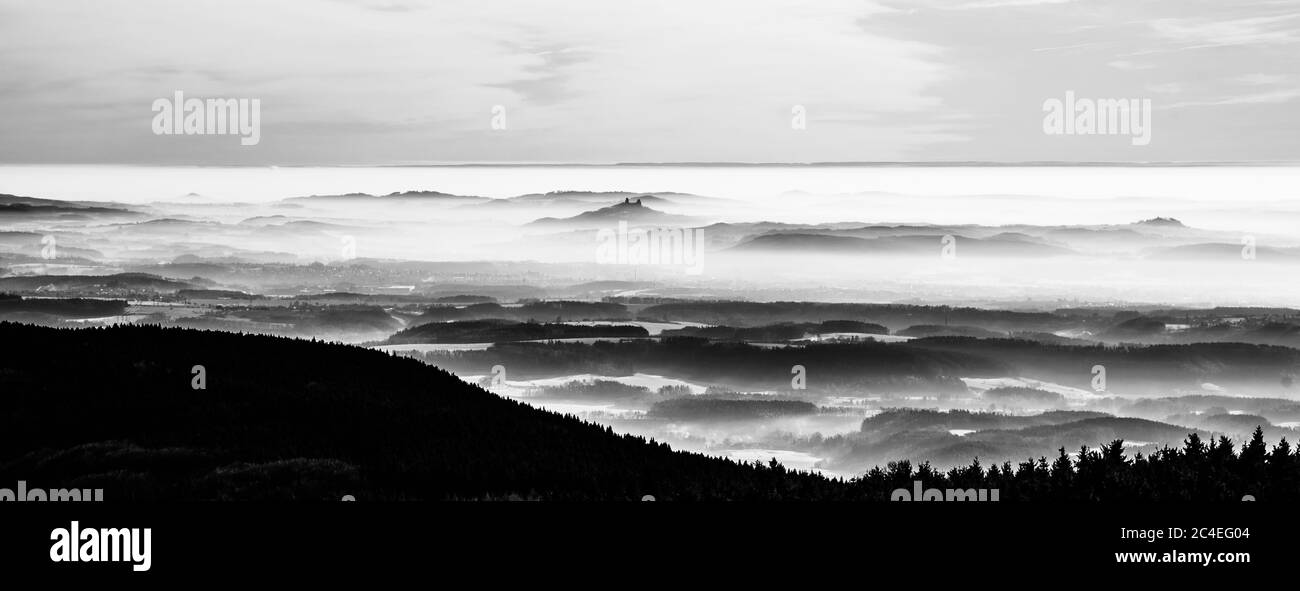 Rovine del castello di Trosky che si innalzano dalla nebbia. Inversione della temperatura meteo, Repubblica Ceca. Immagine in bianco e nero. Foto Stock