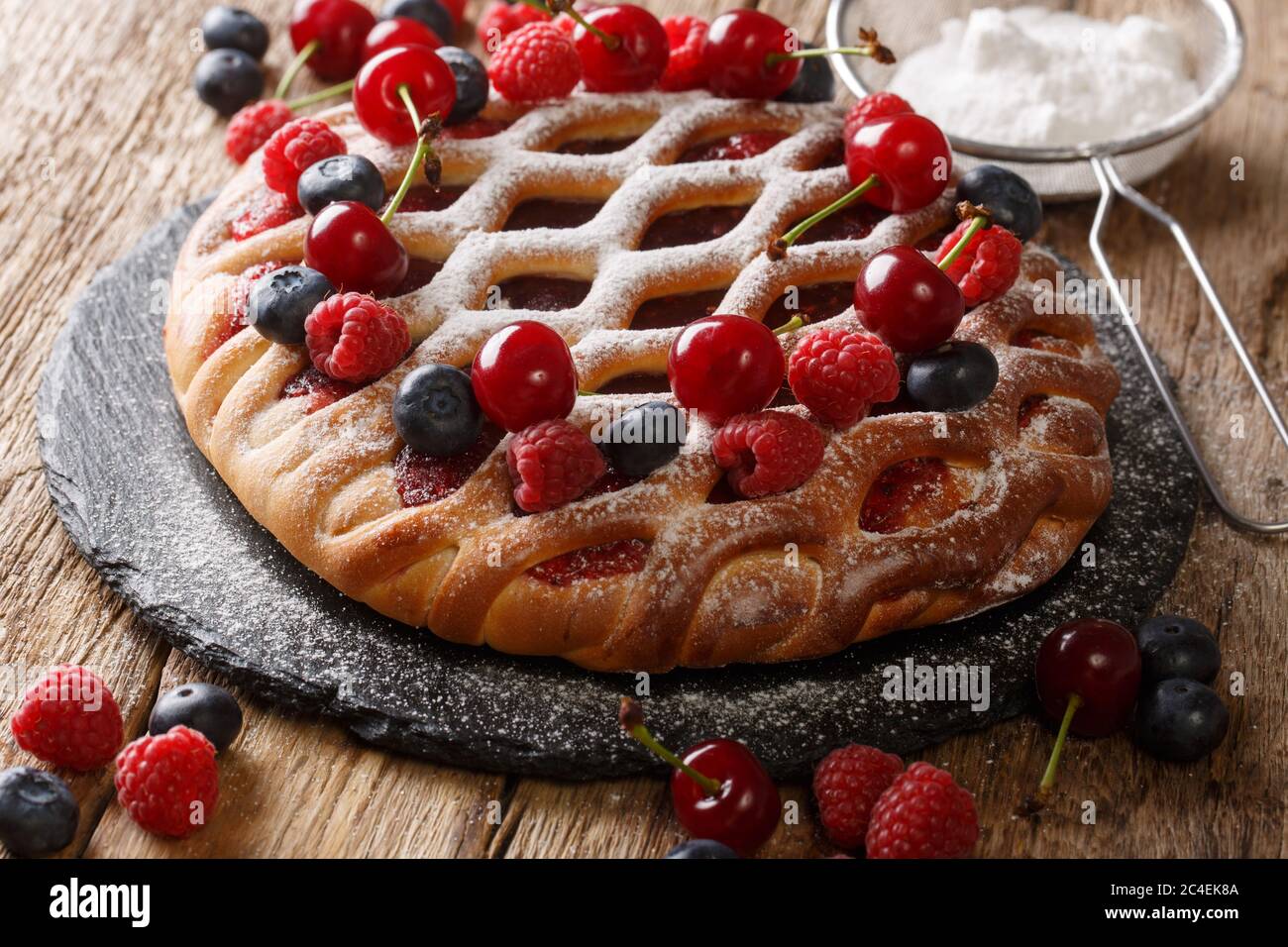 Torta di frutti di bosco appena sfornata con lamponi, mirtilli e ciliegie primo piano su un tavolo di ardesia. Orizzontale Foto Stock