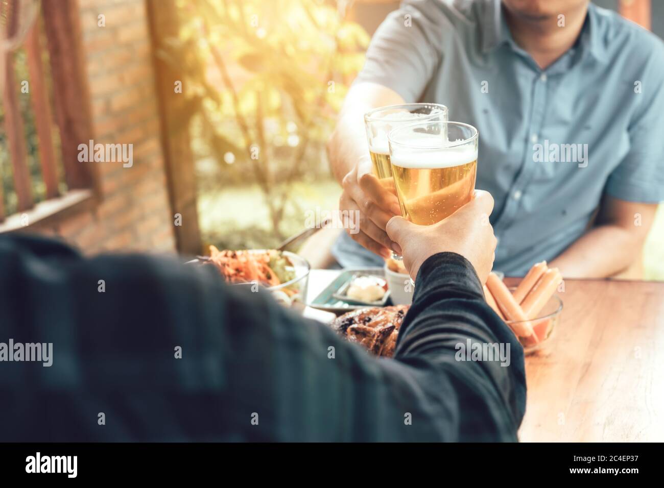 Primo piano di un uomo adulto a mano che tiene un bicchiere di birra e che si aggraffa insieme. Foto Stock