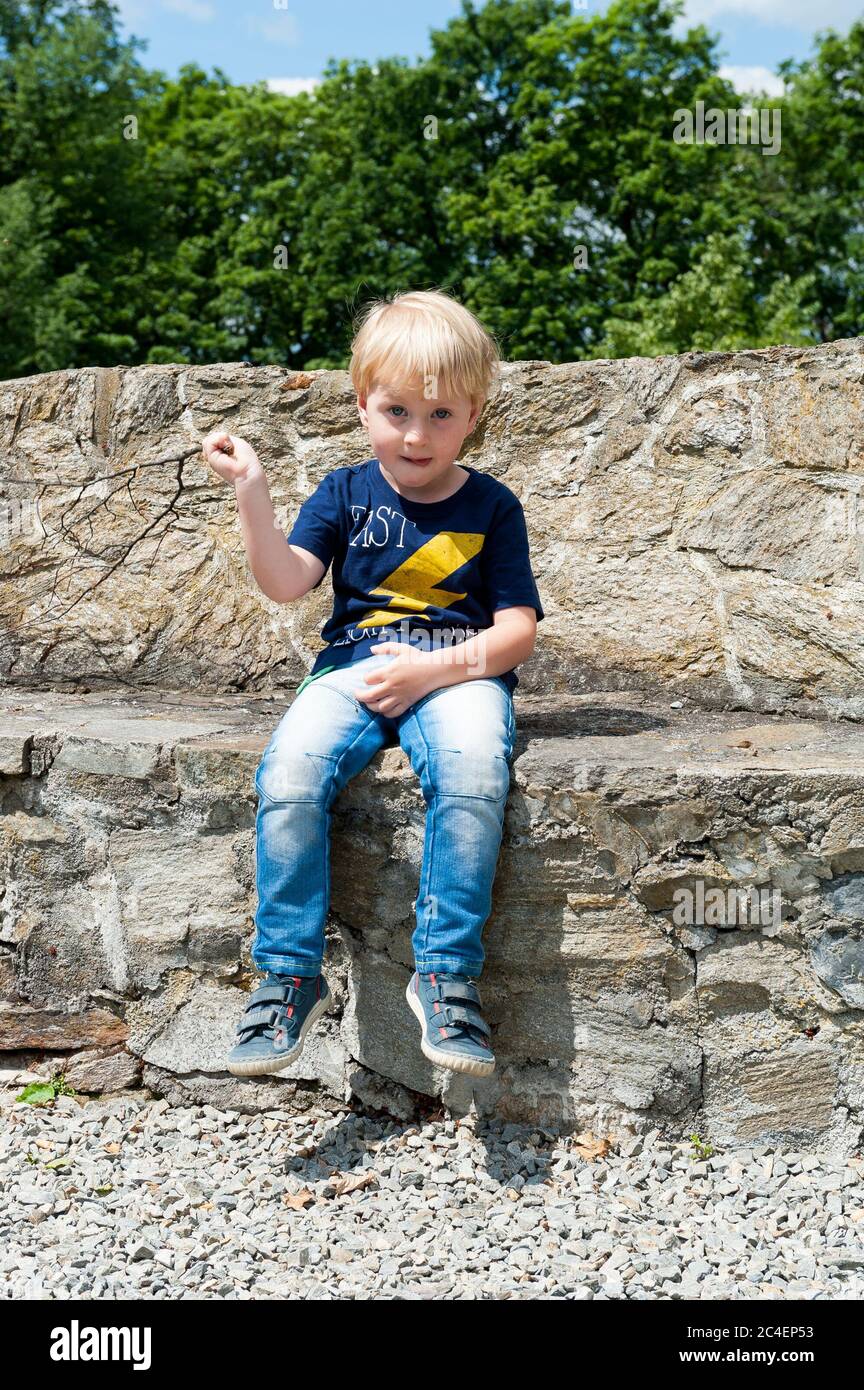 Ragazzo di tre anni seduto su un muro accanto al sontuoso castello di Kamieniec Ząbkowicki, nella contea di Ząbkowice Śląskie, basso Voivodato della Slesia, Polonia Foto Stock