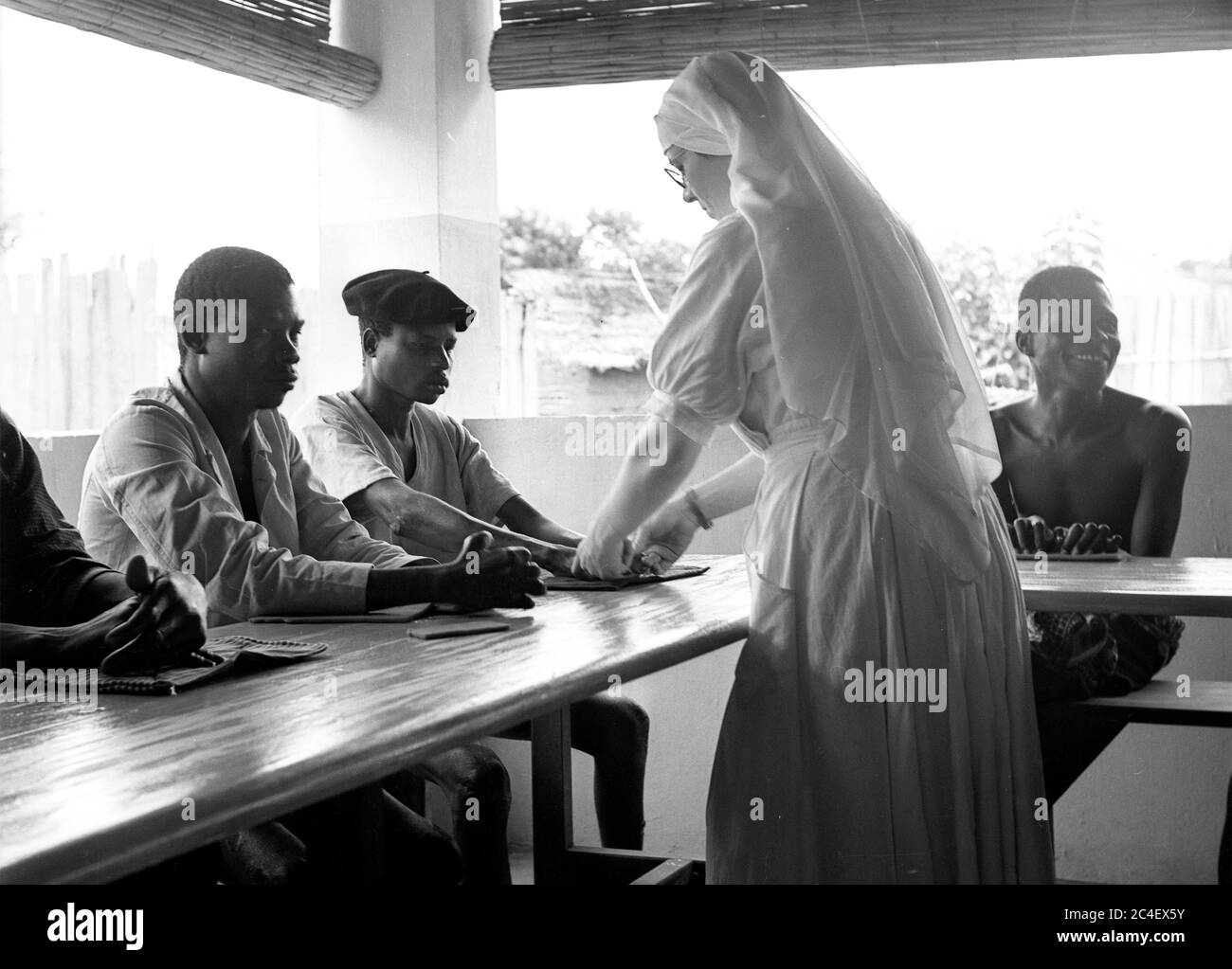 Nun Missionario che controlla le mani dei giovani in Costa d'Avorio 1963 Costa d'Avorio anni '60 Foto Stock