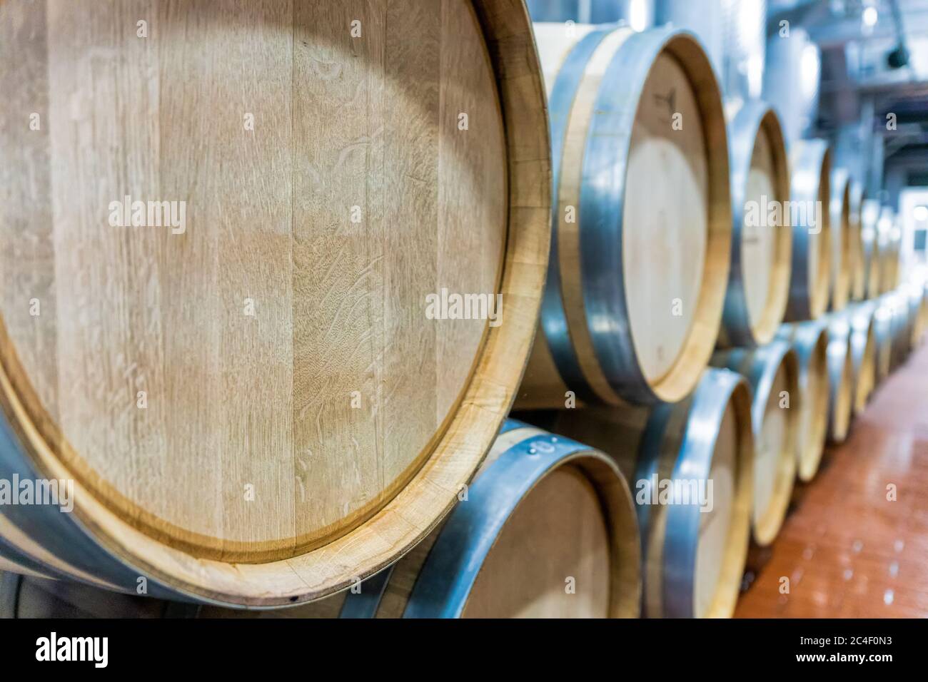 Messa a fuoco selettiva. Fila di grandi botti di vino rosso di quercia francese in un moderno magazzino di vini Foto Stock