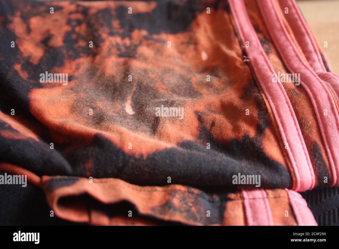 tessuto nero con candeggina e amuchina con macchie rosse e arancioni Foto  stock - Alamy