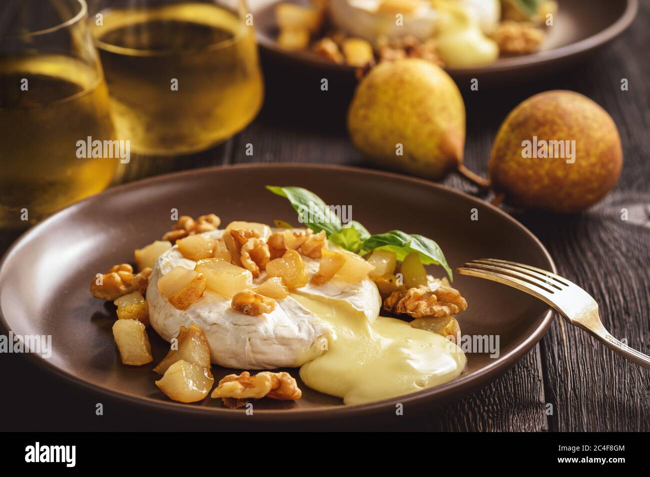 Camembert al forno con pere e noci, servito con vino bianco. Foto Stock