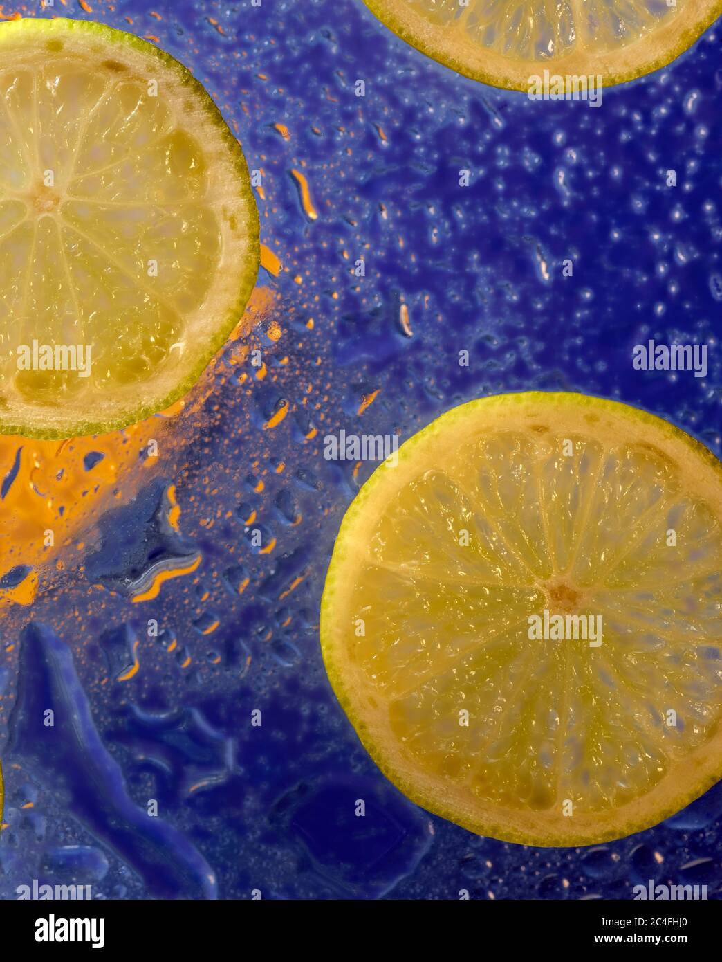 Affettato di lime verde e di gocce d'acqua colorate su una superficie dura, primo piano food art Foto Stock