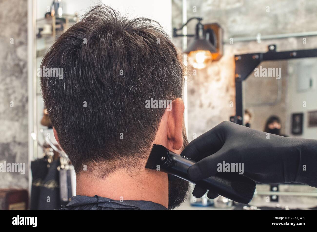 Barbiere taglio capelli sul collo e nuca di uomo in barbiere con strumento  professionale regolacapelli. Rifinitore elettrico per tagliare i capelli  sulla pelle del cliente Foto stock - Alamy