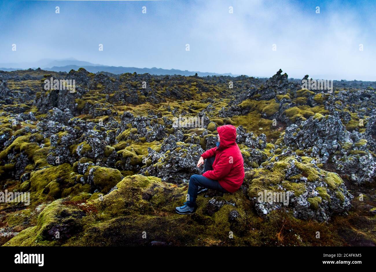 Solo viaggiatore maschile con vista panoramica del campo di lava in Islanda Foto Stock