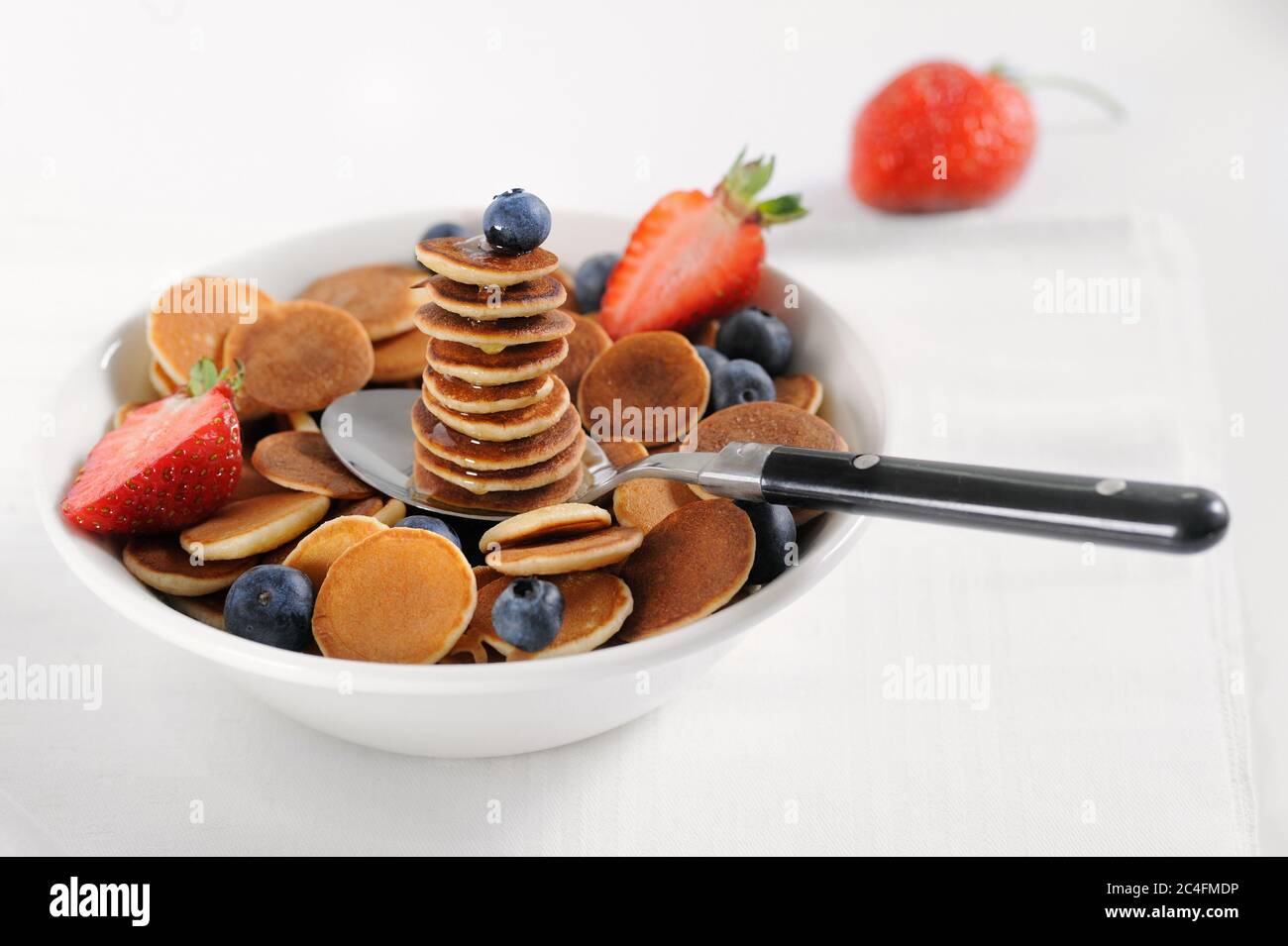 Una pila dolce fatta in casa di frittelle con miele, mirtillo fresco, fragole su sfondo chiaro. Spazio per testo.primo piano.orizzontale, selettivo Foto Stock