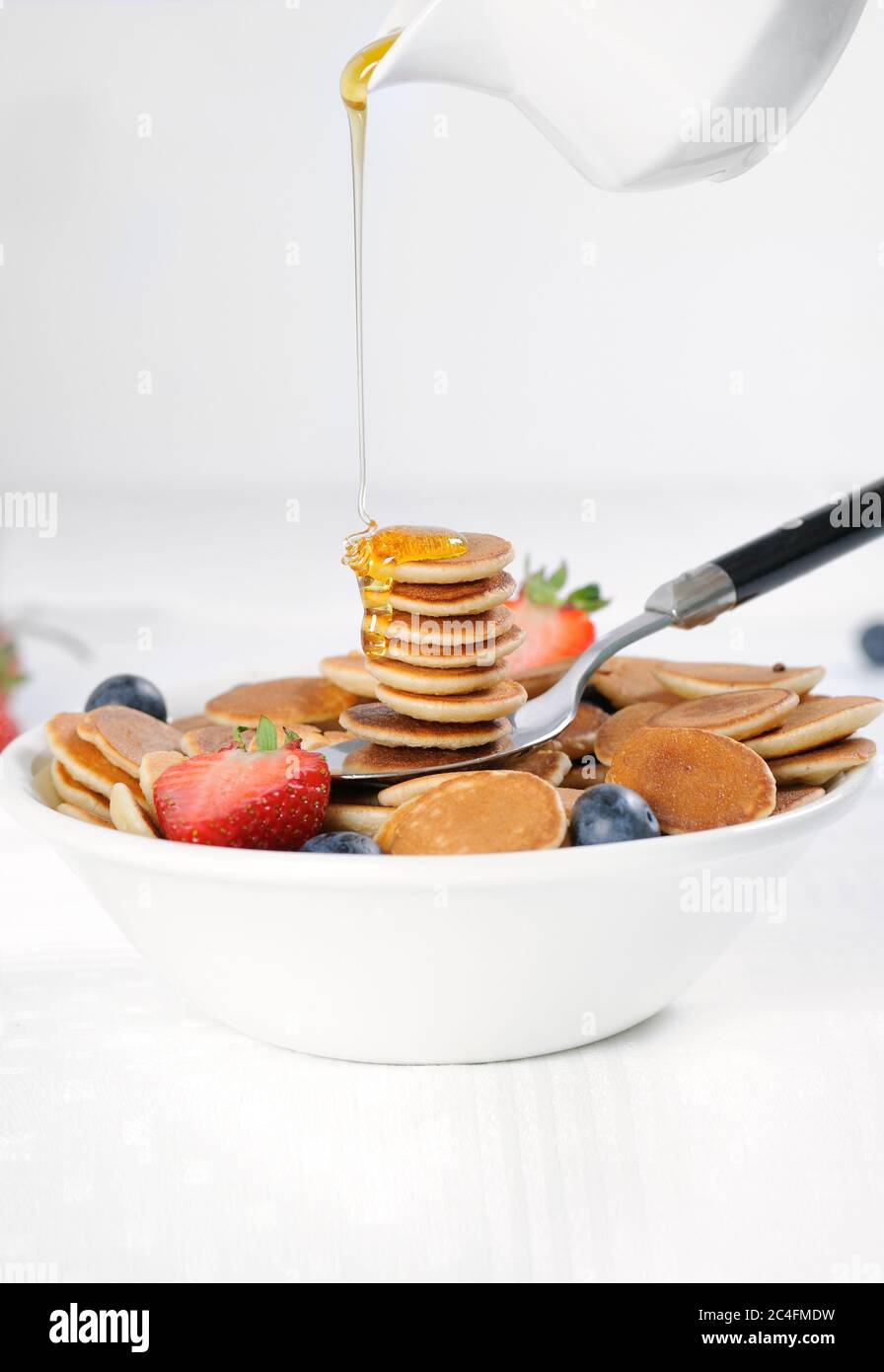 Gustosa colazione con mini pancake di cereali con fragole e mirtilli. Mini pancake di cereali è nuovo cibo alla moda per le attività. Foto Stock
