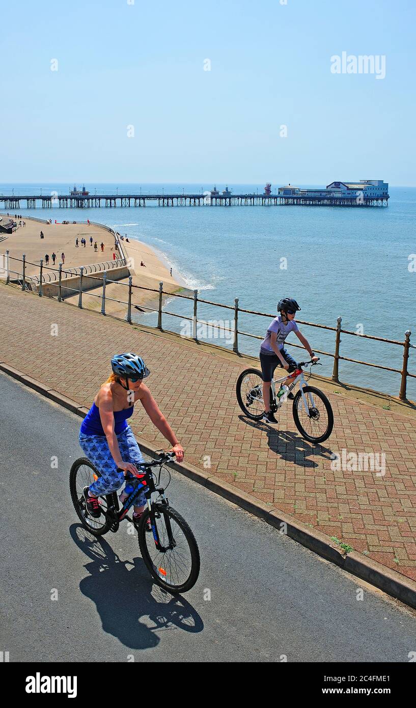 Donna e ragazzo in bicicletta lungo Blackpool Promenade con Nord Pier sullo sfondo Foto Stock
