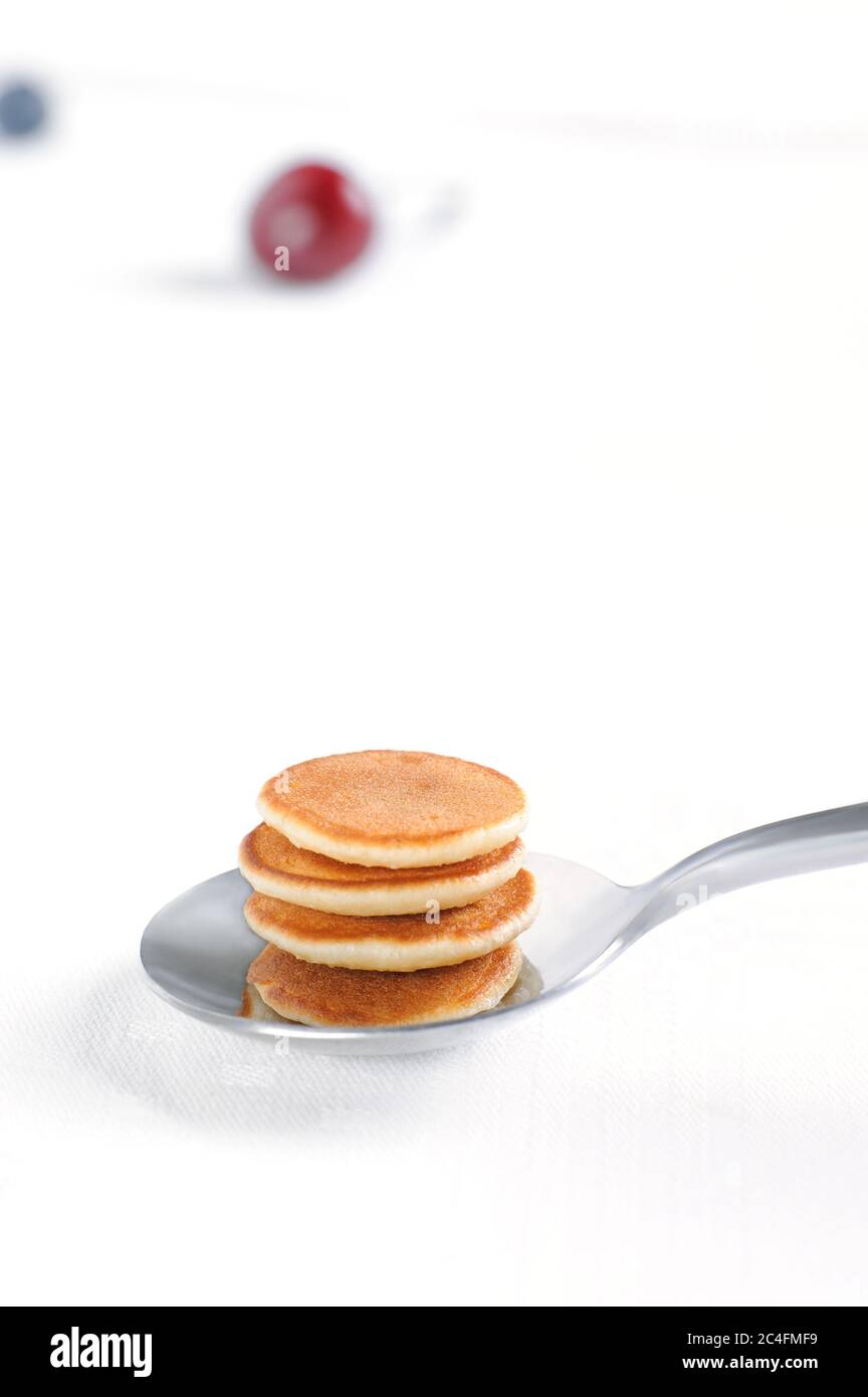 Sul cucchiaio sono fatte in casa minuscoli pancake di cereali. Colazione alla moda. Orientamento verticale. Foto Stock