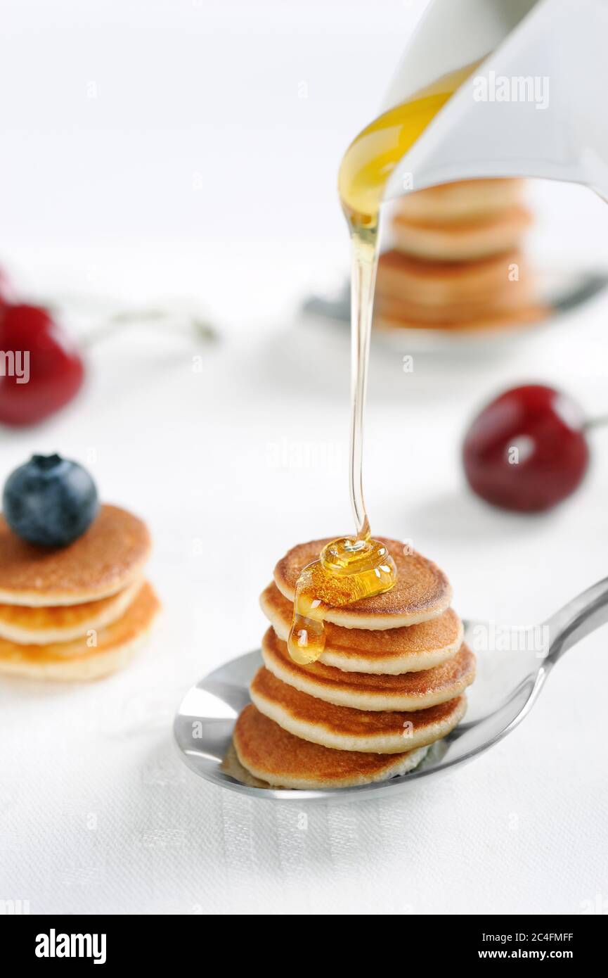 Gustosa colazione con mini pancake cereali con fragole e mirtilli. Mini pancake cereali è nuovo cibo alla moda per attività. Orientamento verticale. Foto Stock