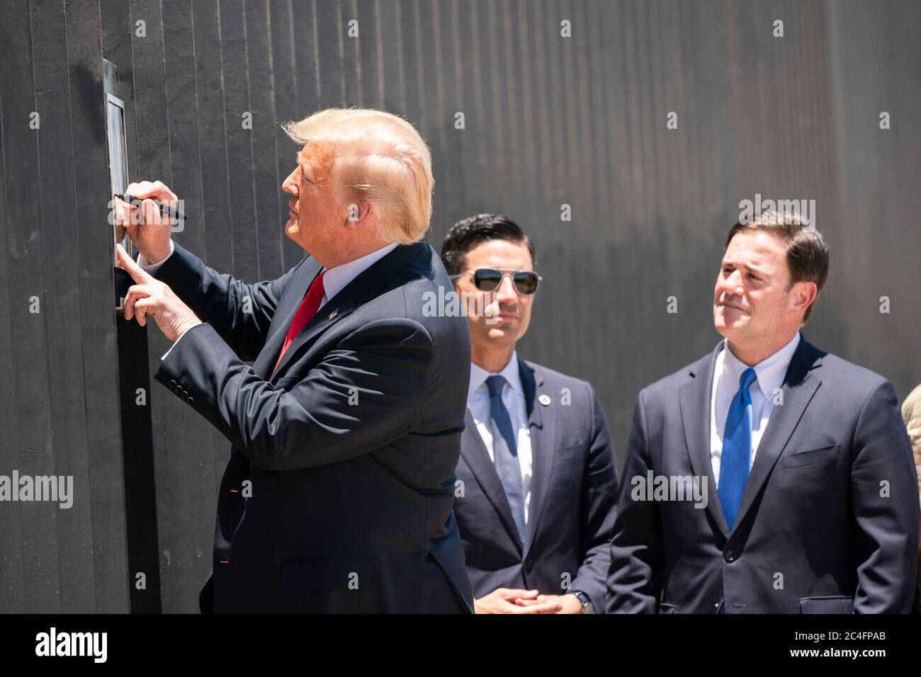 Il presidente degli Stati Uniti Donald Trump firma una targa su una nuova sezione del muro di confine lungo il confine messicano-americano come segretario del DHS Chad Wolf e Arizona Gov. Doug Ducey, a destra, guarda il 23 giugno 2020 a San Luis, Arizona. Foto Stock