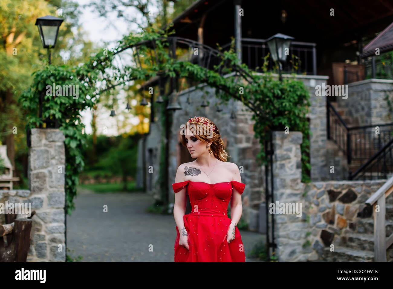 Donna tattoed rosso in abito vicino al castello Foto Stock