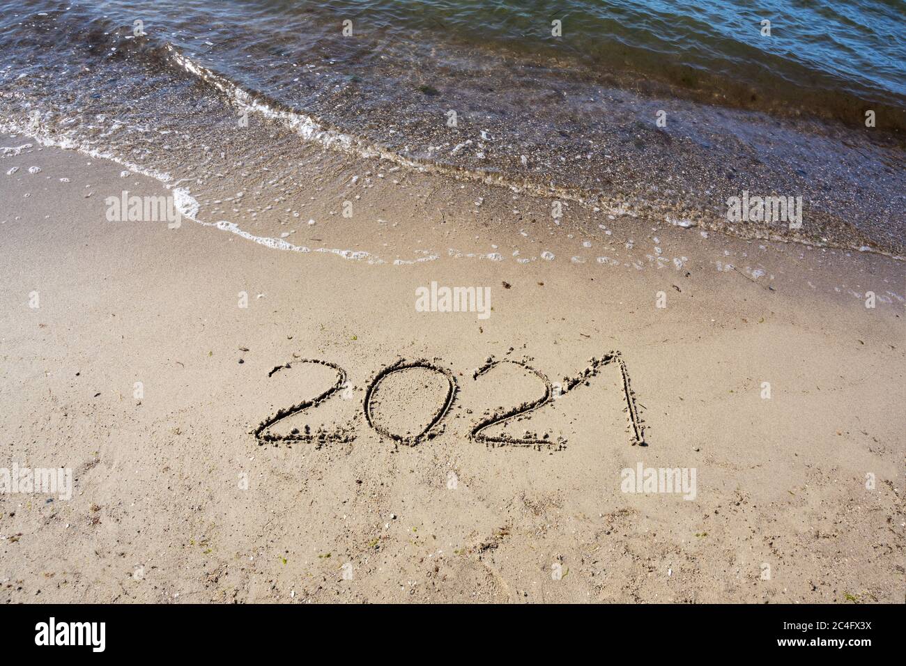 2021 scritto nella sabbia sulla spiaggia per un felice anno nuovo, ma l'acqua verrà, copia spazio, selezionato fuoco Foto Stock