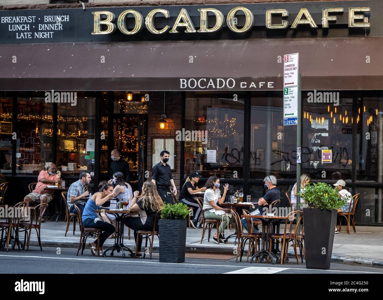 New York, Stati Uniti. 26 Giugno 2020. I camerieri indossano maschere per il viso mentre servono tavoli allestiti per la prima volta in Lexington Avenue, nella parte orientale superiore. I ristoranti sono stati autorizzati ad aprire servizi all'aperto, anche se le persone sono ancora tenute a osservare la distanza sociale, quando la città è entrata in una nuova fase di restrizioni rilassato fissate dall'epidemia di coronavirus. Credit: Enrique Shore/Alamy Live News Foto Stock