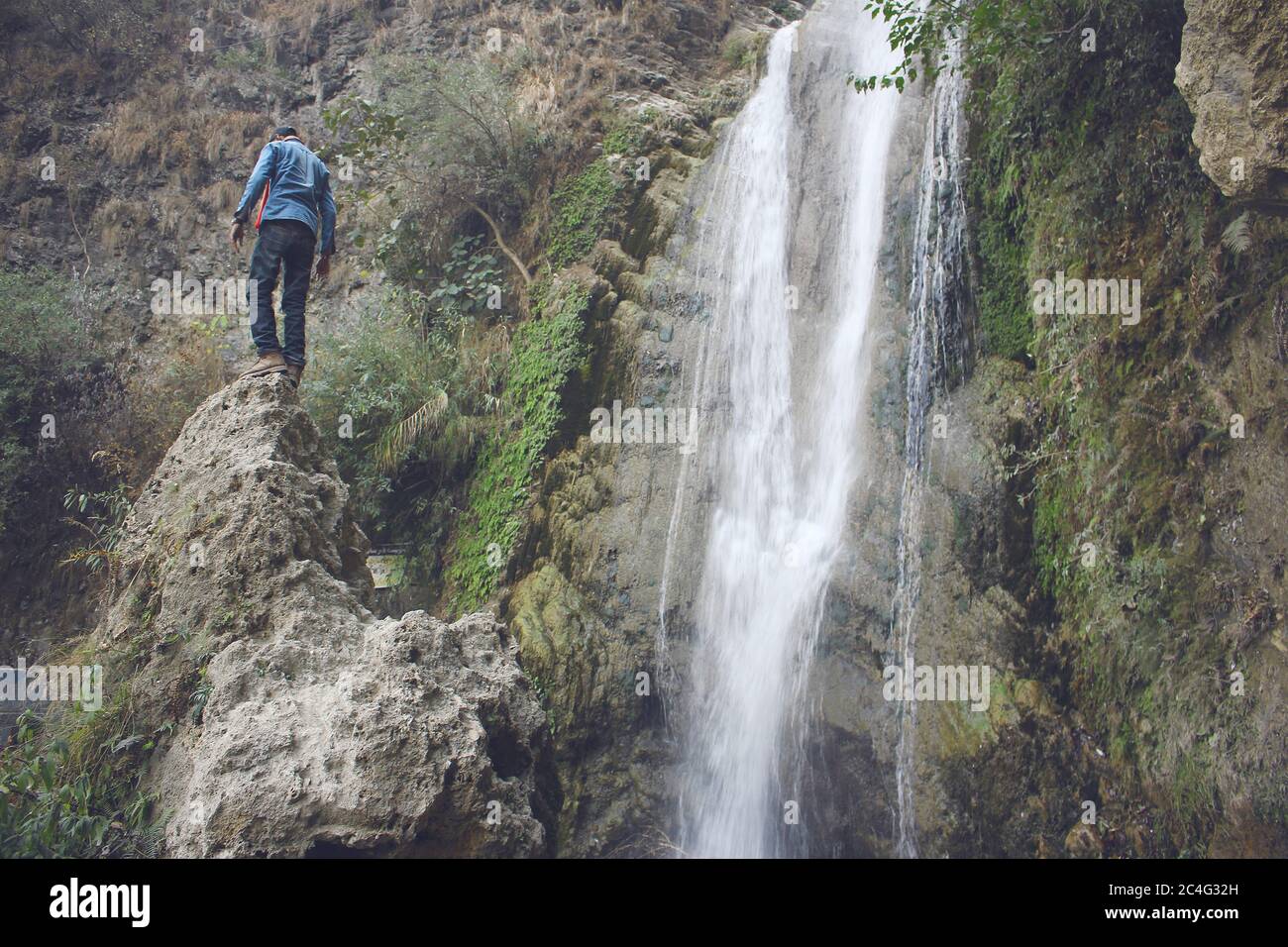 Il viaggiatore si trova su una roccia vicino alla cascata, Kashmir, Pakistan Foto Stock