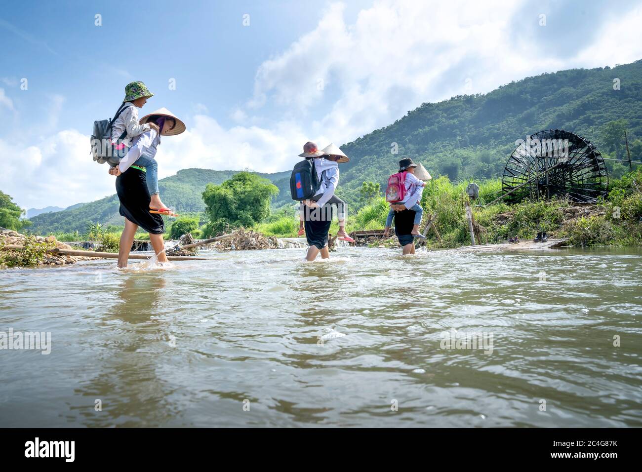 Provincia di Phu Tho, Vietnam - 28 maggio 2020: Le donne di minoranza etnica portano i loro bambini attraverso il grande flusso per andare a scuola Foto Stock