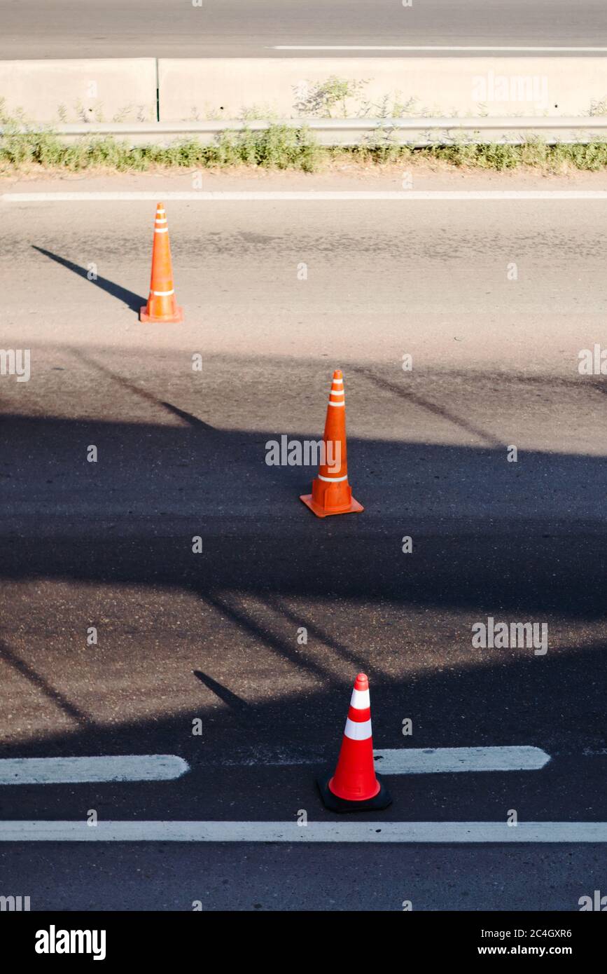 Coni riflettenti arancioni su una strada, utilizzati come misura di calmazione del traffico. Foto Stock