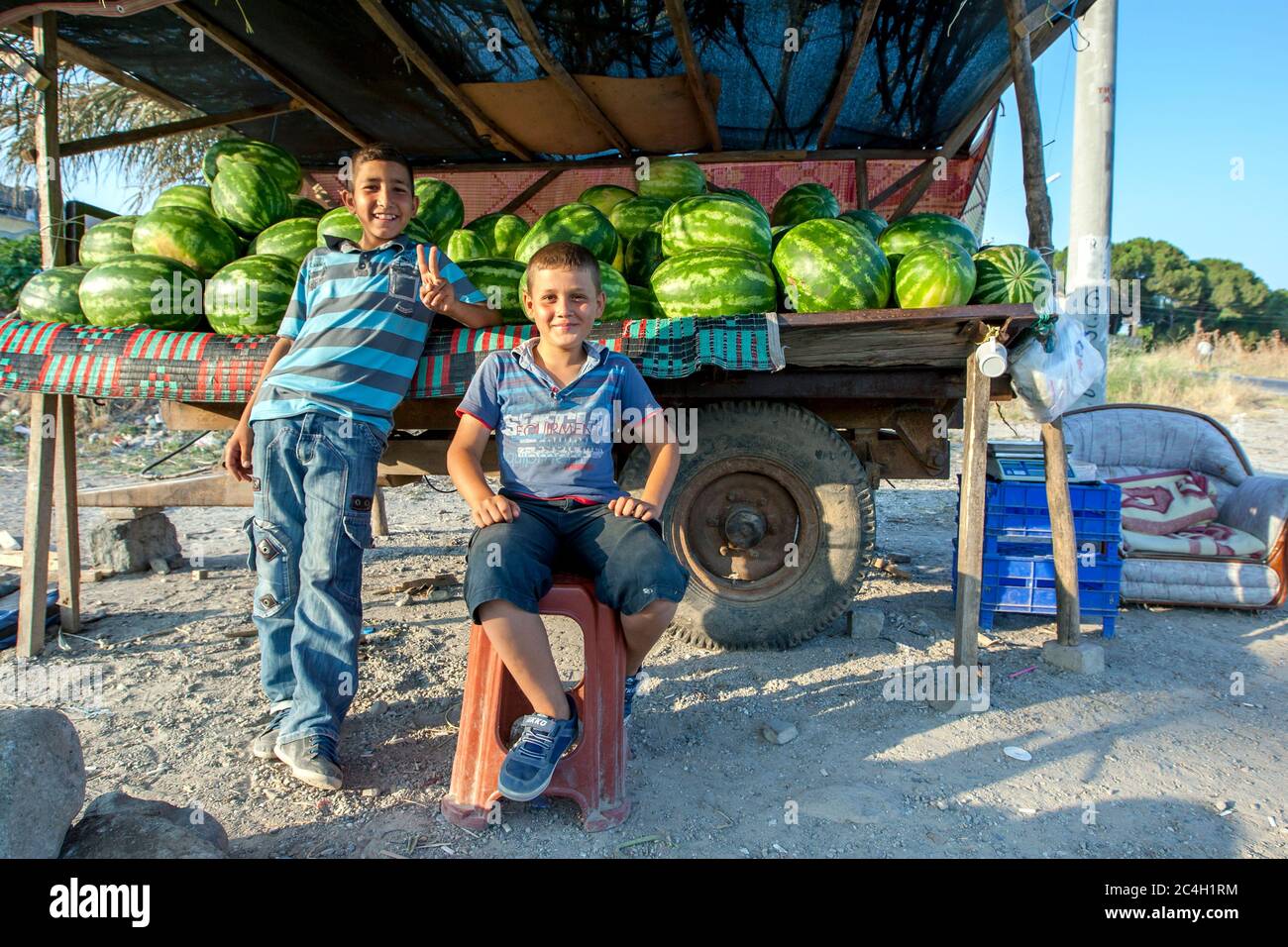 Un uomo e un ragazzo turchi aspettano i clienti al loro chiosco di anguria allestito su un rimorchio alla periferia di Bergama, una città nella Turchia occidentale. Foto Stock