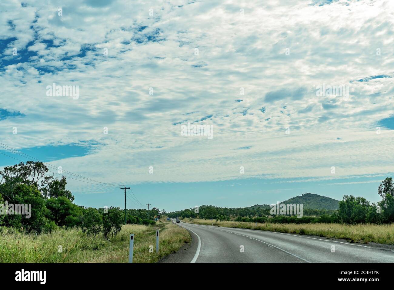 Un'autostrada di campagna australiana sotto un cielo blu nuvoloso Foto Stock