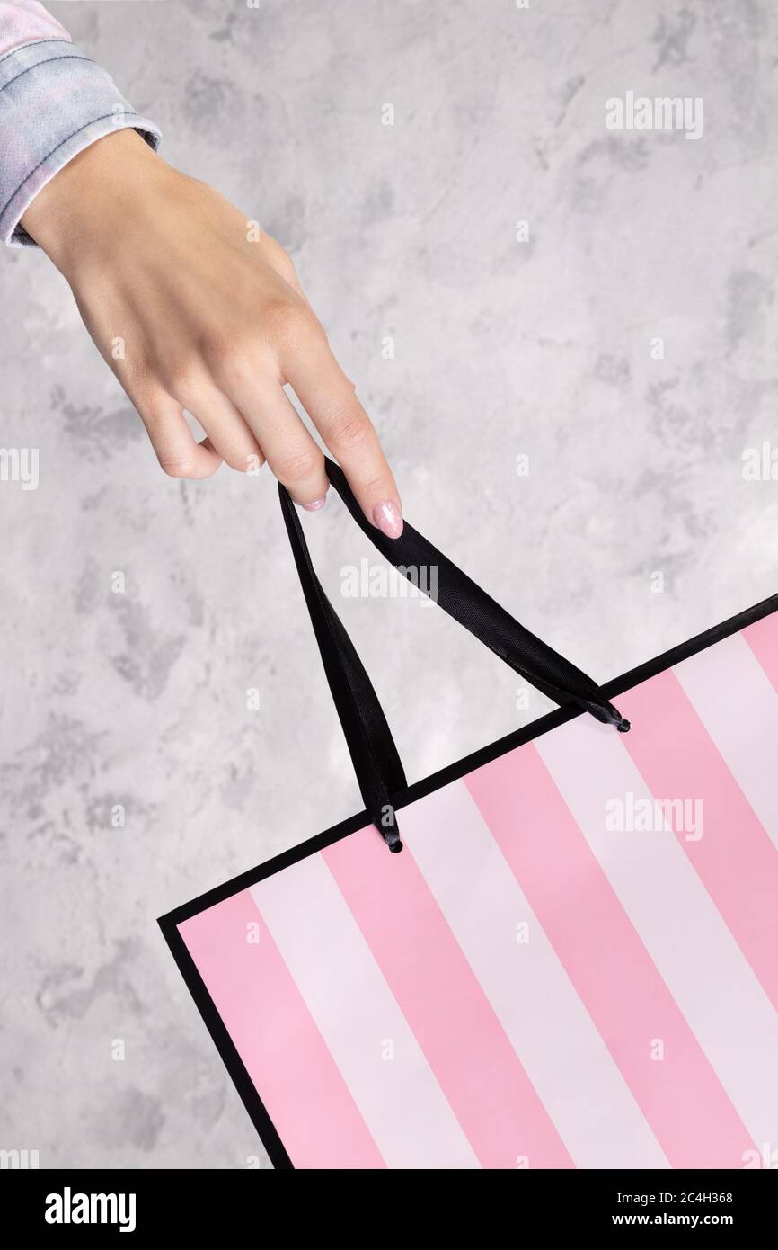 Borsa per la spesa in carta con mano femmina su sfondo grigio in cemento Foto Stock