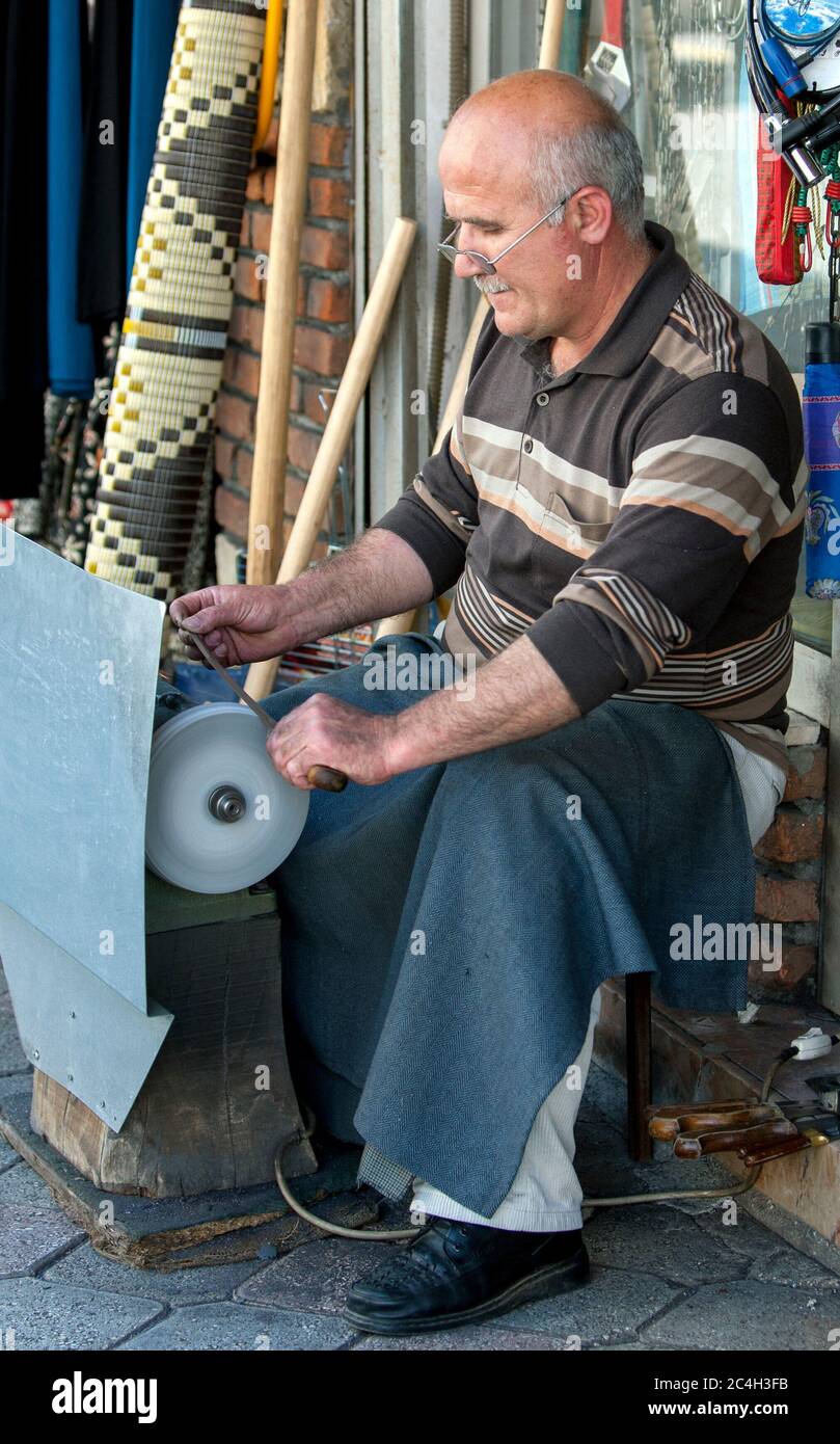 Un uomo affilare lame coltello su una mola nella parte anteriore del suo negozio nella città costiera turchese di Fethiye in Turchia. Foto Stock