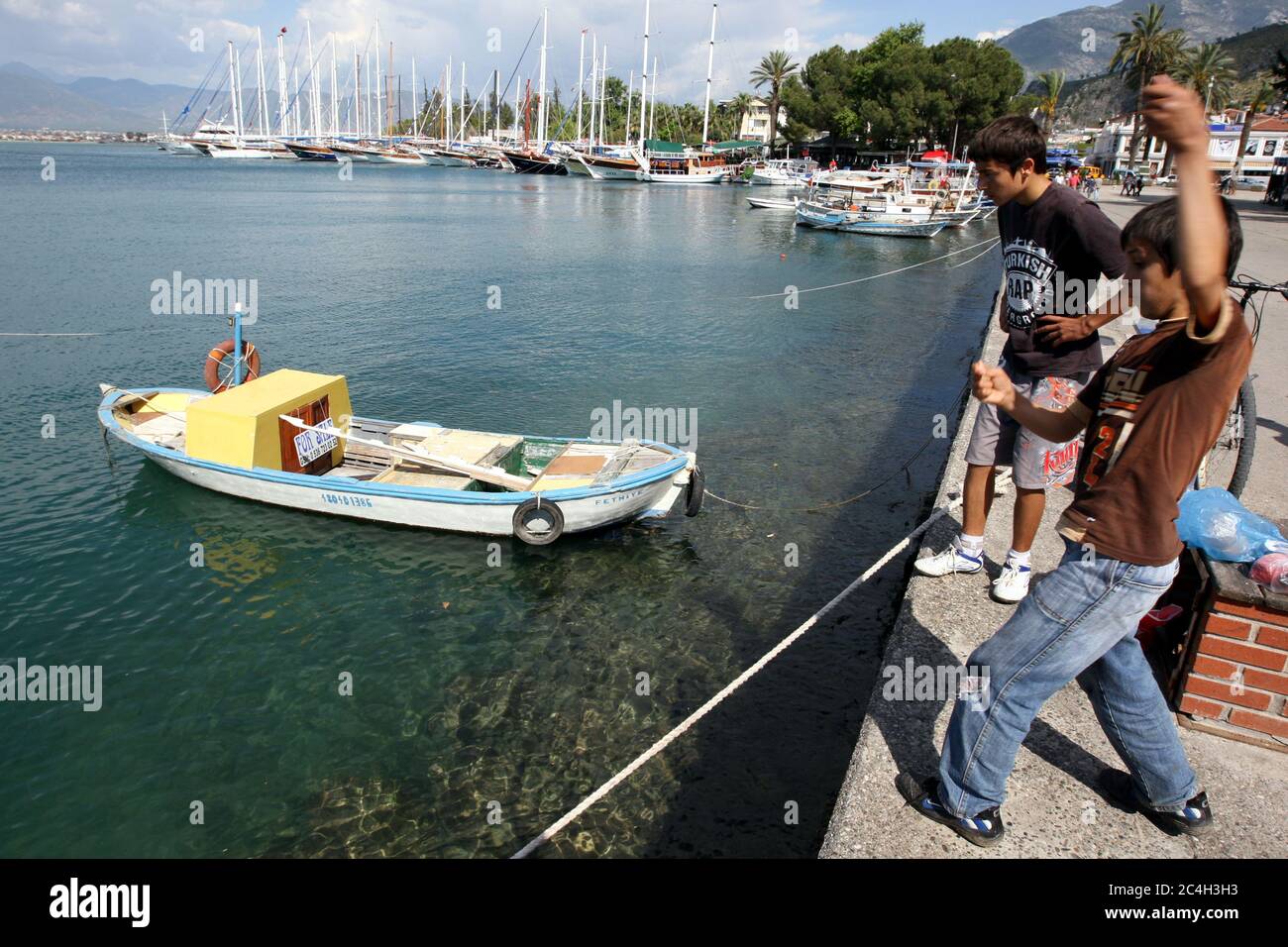 Ragazzi che pescano con una lenza a Fethiye Harbour in Turchia. Fethiye si trova sulla Costa Turchese della Turchia ed è conosciuta per il suo porto naturale. Foto Stock