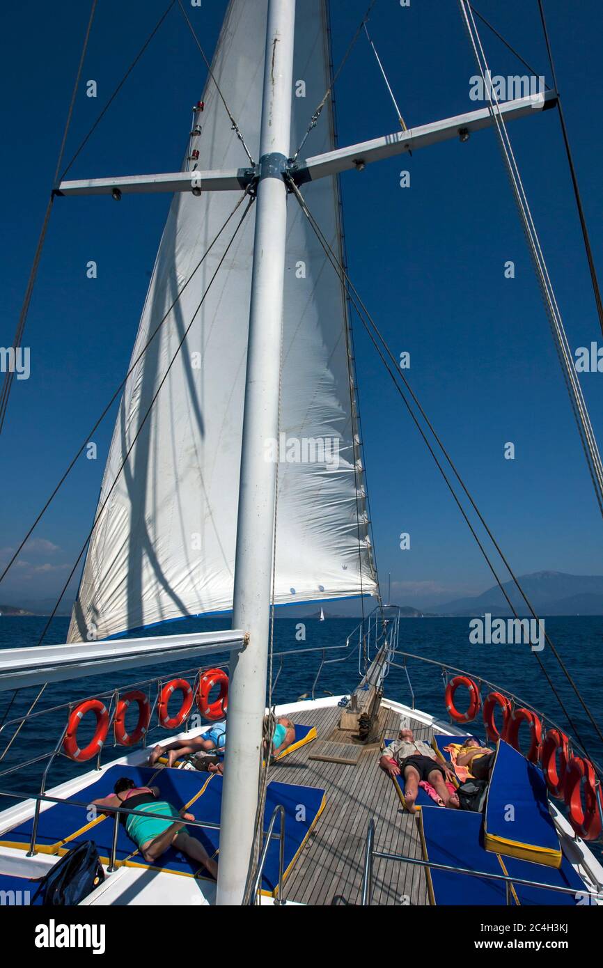 I turisti a bordo di una nave da crociera si rilassano mentre navigano sul Mar Mediterraneo al largo della Costa Turchese di Fethiye in Turchia. Foto Stock