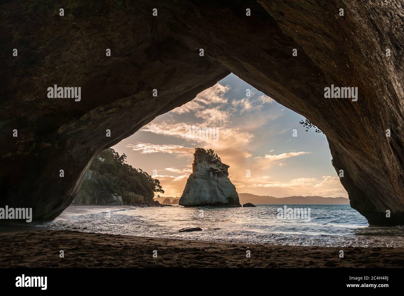 Tramonto, Cove della cattedrale, Penisola di Coromandel, Nuova Zelanda. Vista attraverso il rock arco verso Te Hoho Rock Foto Stock