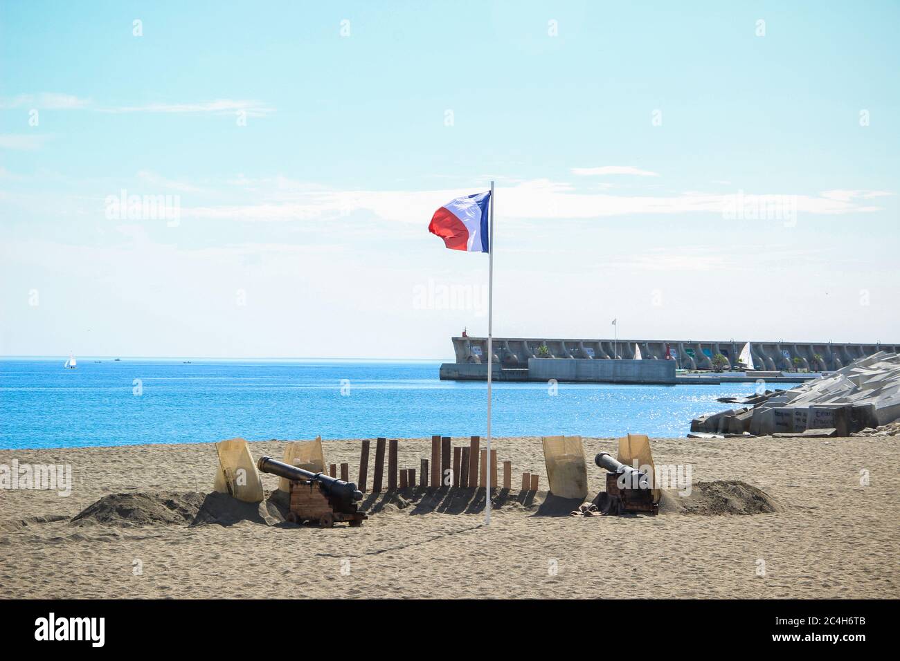Malaga, Spagna - 26 ottobre 2014: Bandiera francese vola tra due cannoni su una spiaggia vicino al porto. Rievocazione storica di un corsaro napoleonico Foto Stock