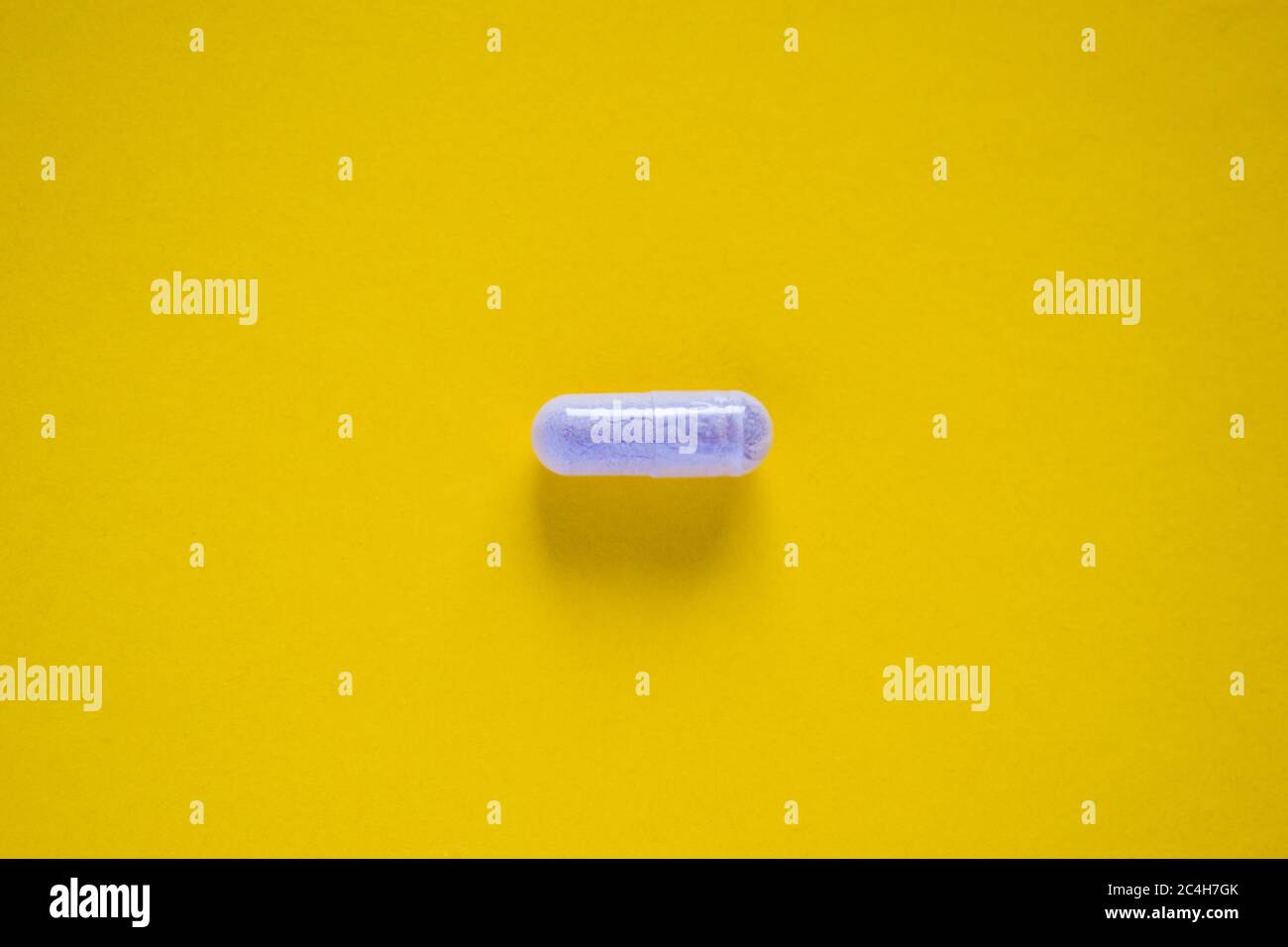 Una pillola medica bianca su sfondo giallo Foto Stock