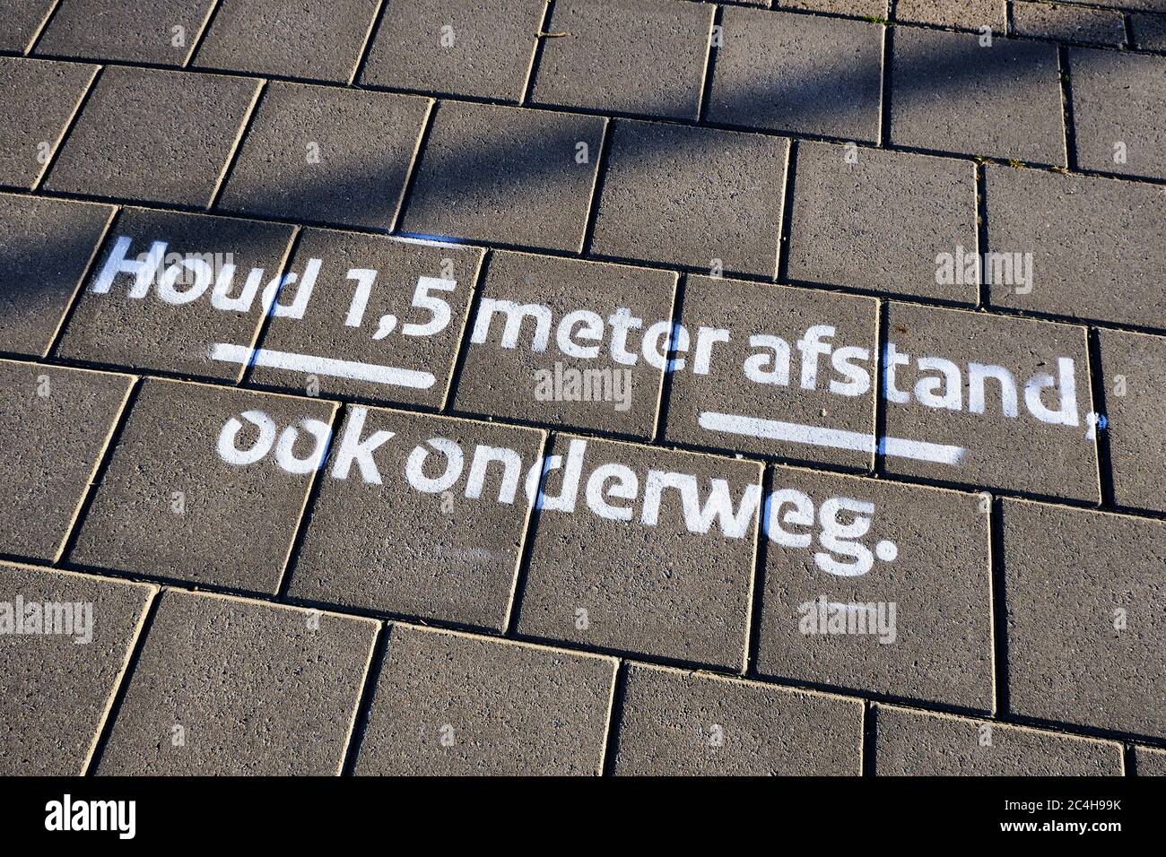 Disegnare sulla pavimentazione in lettere olandesi significa: "Mantenere una distanza sociale di 1.5 metri, anche sulla strada". Misure e norme sul coronavirus Foto Stock