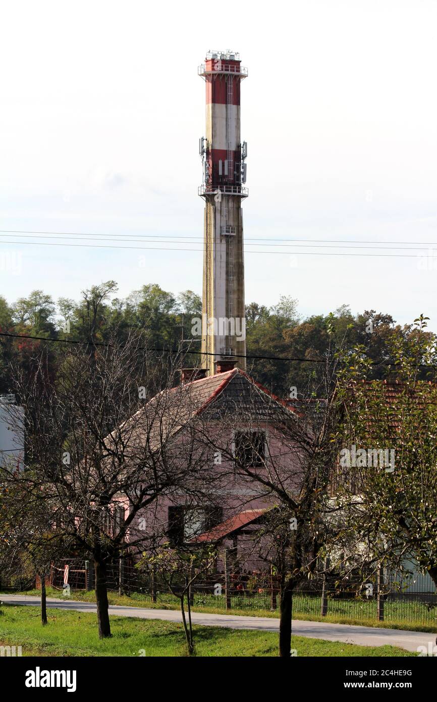 Camino industriale rettangolare rosso e bianco vecchio calcestruzzo sporco con due piattaforme di sicurezza in metallo e più antenne e trasmettitori per telefoni cellulari Foto Stock