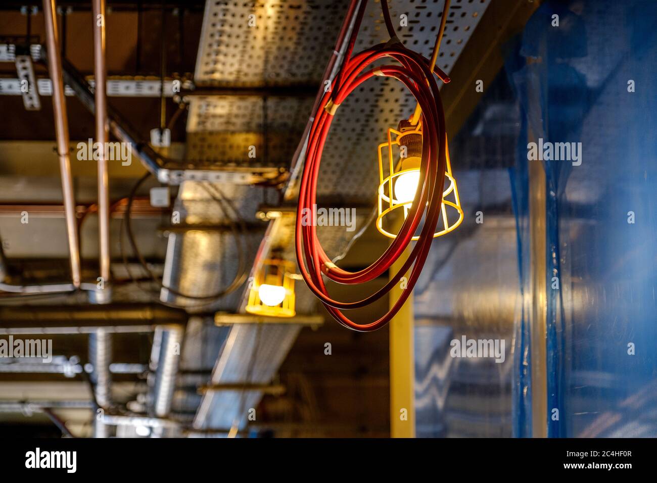 La bobina del cavo elettrico è sospesa dal soffitto per la luce di lavoro nell'edificio in costruzione Foto Stock