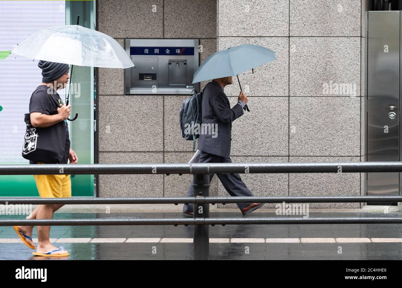 Pedoni con ombrello a piedi al marciapiede di via Roppongi durante una giornata di pioggia, Tokyo, Giappone Foto Stock