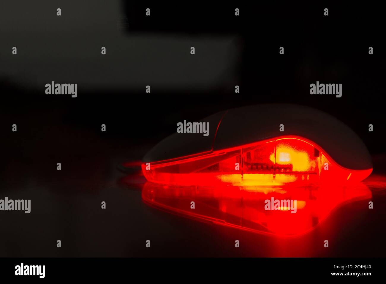 Un mouse al buio. Il mouse è incandescente e i componenti possono essere visti vagamente all'interno del mouse attraverso la plastica traslucida. La luce è refl Foto Stock
