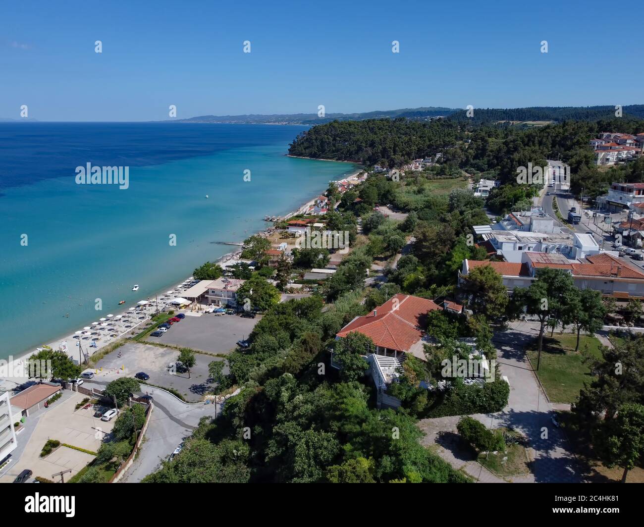 CHALKIDIKI, Grecia villaggio costiero paesaggio drone colpo con pini. Vista aerea di giorno sul lungomare di Kallithea sulla penisola di Kassandra con bar sulla spiaggia Foto Stock