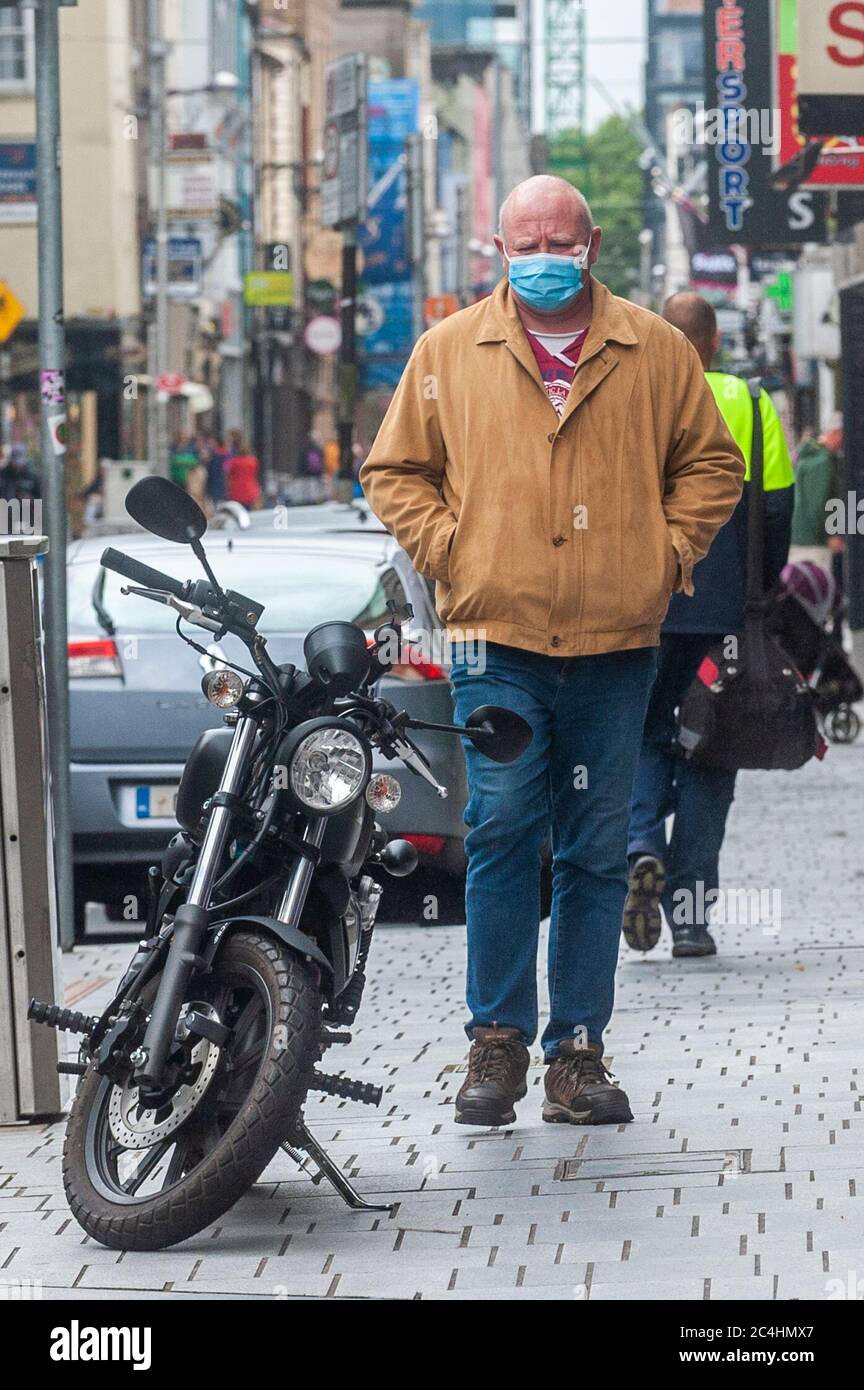 Cork, Irlanda. 27 Giugno 2020. Un uomo cammina nella città di Cork indossando una maschera per proteggersi dal Covid-19. Il governo sta allentando più restrizioni di Coronavirus lunedì 29 giugno, permettendo a più aziende di riaprire, compresi parrucchieri e hotel. Credit: Notizie dal vivo di AG/Alamy Foto Stock