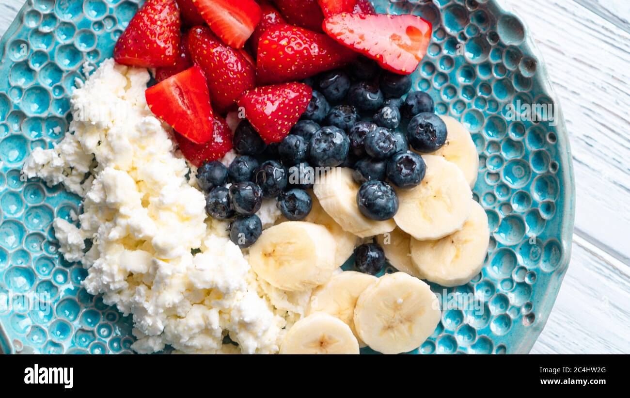 Piacere di mattina. Sana colazione estiva. Formaggio di cottage con frutti di bosco e miele. Colazione accogliente e facile Foto Stock