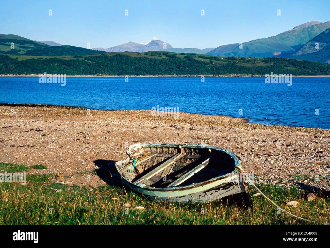 Barca a remi abbandonata su una spiaggia di ciottoli, Scozia. REGNO UNITO. Vista sulla montagna ben Nevis sullo sfondo Foto Stock