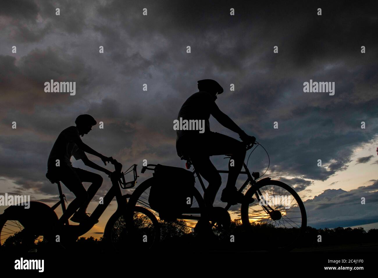 Due ciclisti si dirigono a casa sotto i cieli pesanti Foto Stock