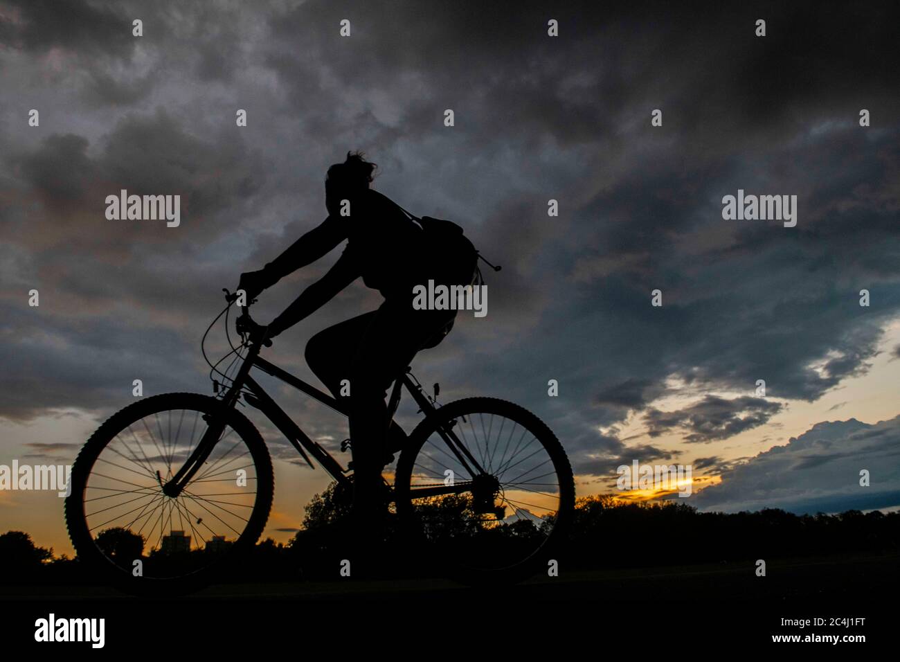 Un ciclista si dirige a casa sotto i cieli pesanti Foto Stock
