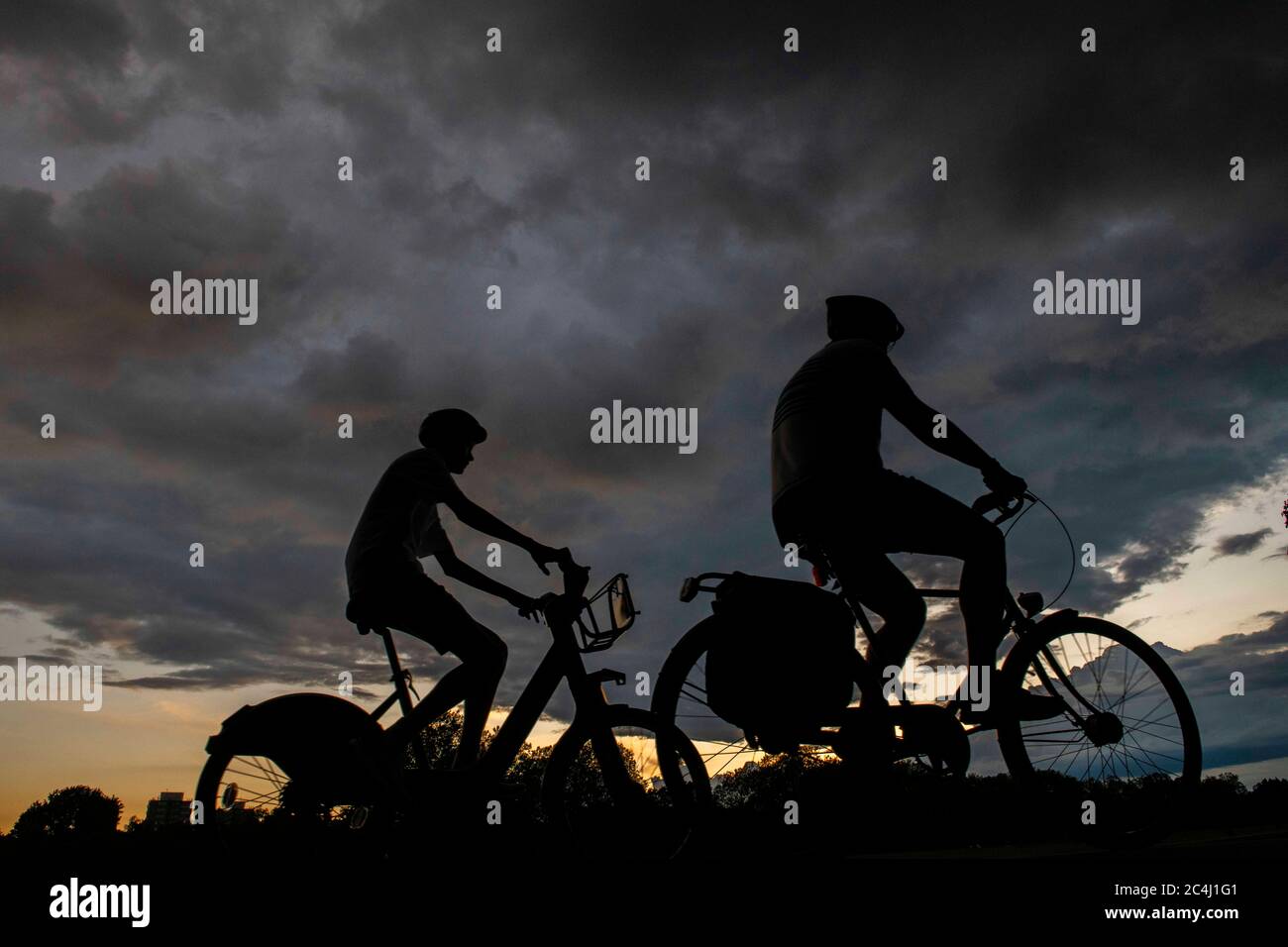 Due ciclisti si dirigono a casa sotto i cieli pesanti Foto Stock