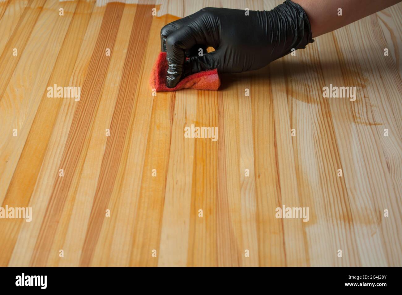 Dipingere un guanto nero. Pittura con una spugna da cucina su un tavolo di legno. Trattamento di una superficie di legno per la protezione contro l'invecchiamento, l'umidità, Foto Stock