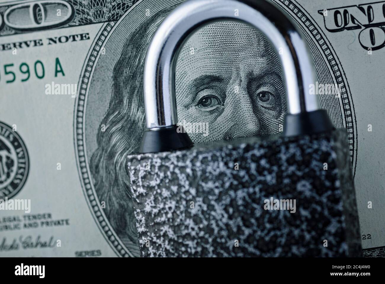 Lucchetto giacente su un dollaro fattura su ritratto di Franklin con fuoco ai suoi occhi attraverso il gambo di acciaio in un concetto di sicurezza finanziaria Foto Stock