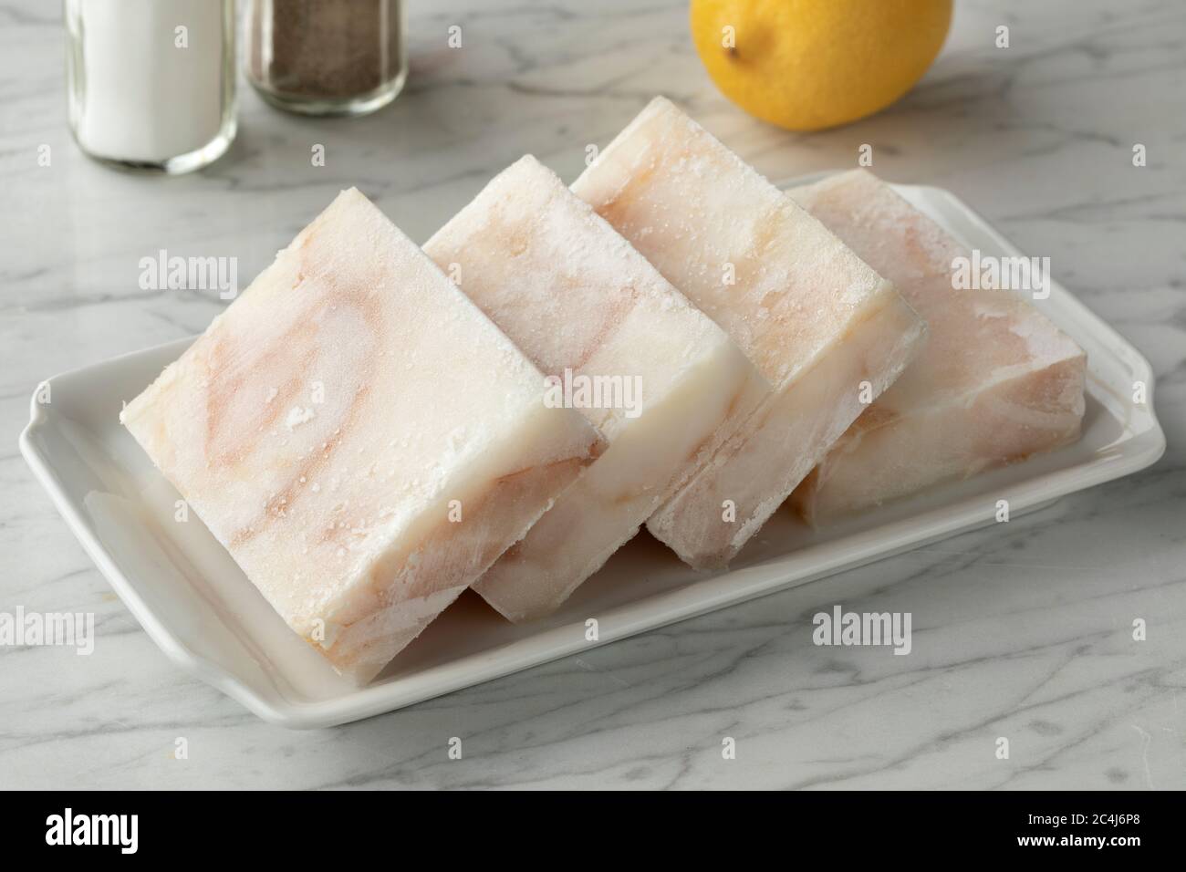 Piatto con filetti di pesce di merluzzo surgelati a fette per scongelare come ingrediente per cucinare Foto Stock